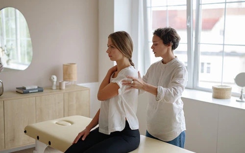 Swedish massage therapy session, therapist applying long strokes to her back